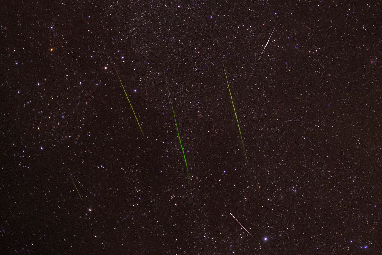 Bright meteors streak across a starry night sky during a captivating shower.